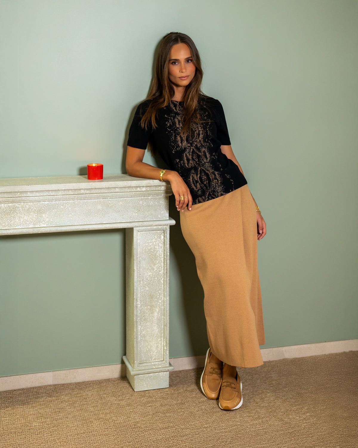 Pull Elsa noir à motif python bronze, porté avec une jupe camel