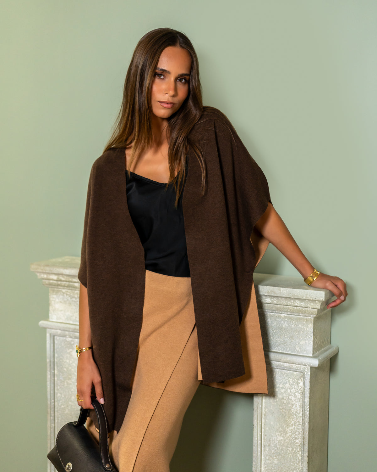 Cape Ira en maille brune, portée ouverte sur un top noir et une jupe camel